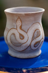 Ceramic vase with snake design on a blue surface