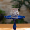 Ceramic cup with decorative design on a blue stand against a blurred natural background